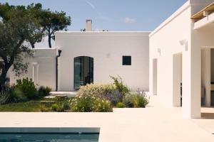 a white house with a pool in front of it at Masseria Pietra e Terra in Carovigno