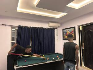 two men standing in a room with a pool table at Apartment in Alakuko in Akinde