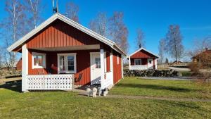 a small red and white house with two dogs standing outside at B & B Flattinge Fritidshus in Vittaryd