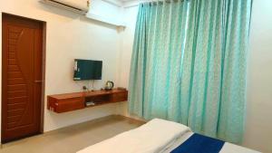 a room with a bed and a television and a door at Bellevue Retreat in Alībāg