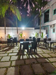a patio with tables and chairs and palm trees at Bellevue Retreat in Alībāg
