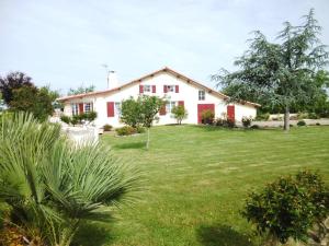 a white house with red doors and a yard at Maison jeanborde in Serreslous-et-Arribans