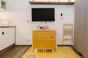 a tv on a wall with a wooden dresser at Lambrusco - Harbor's Light in Villajoyosa