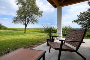 ein Stuhl und ein Tisch auf einer Veranda mit einem Feld in der Unterkunft 23 Mattenham - Rückzugsort in Abgeschiedenheit in Vilshofen an der Donau + 10 Fotos