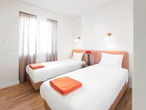 a hotel room with two beds and a window at LSA Restauradores by Numa in Lisbon