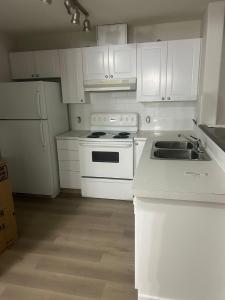a white kitchen with a stove and a sink at Your private room CozyVibe in Edmonton