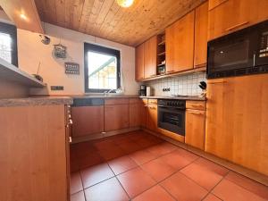 a kitchen with wooden cabinets and an orange tile floor at Ferienwohnung Buronia 2 in Kaufbeuren +5 photos