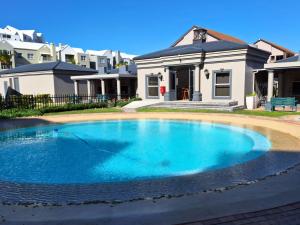 a large blue swimming pool in front of a house at Merve's Place - Portobelo 48 in Mossel Bay