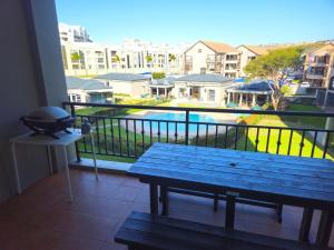 a balcony with a picnic table and a view of a city at Merve's Place - Portobelo 48 in Mossel Bay
