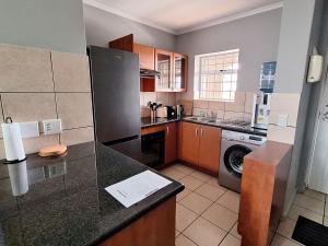 a kitchen with a counter top and a washer at Merve's Place - Portobelo 48 in Mossel Bay +4 photos