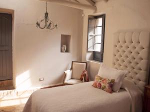 a bedroom with a bed and a chair and a chandelier at Hotel MasClara in Villa de Leyva