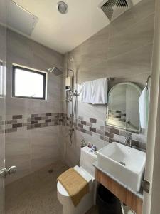 a bathroom with a sink and a toilet and a mirror at Yalyn's Hometel Kabankalan in Kabankalan