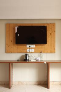 a flat screen tv on a wall above a table at Sufi stay in Rishīkesh