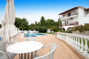 a patio with a table and chairs and a pool at Villa Alissia in Koukounaries