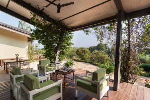 a patio with chairs and a table on a deck at SaffronStays Vinayalam in Mahabaleshwar