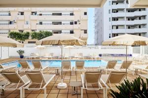 a pool with chairs and umbrellas on a building at Apartamentos Mar i Vent in San Antonio