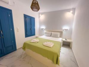 a bedroom with a bed with green sheets and blue doors at Amorgona Apartments in Katapola