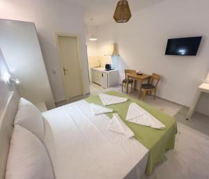 a room with a bed with a table and a kitchen at Amorgona Apartments in Katapola