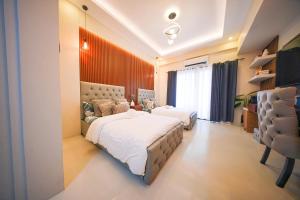 a bedroom with two beds and a desk and a television at Alpine Villas at Crosswinds Tagaytay Casa de Vela in Tagaytay