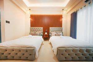 two beds in a hotel room with white sheets at Alpine Villas at Crosswinds Tagaytay Casa de Vela in Tagaytay