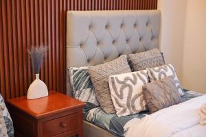 a bed with pillows and a vase on a table at Alpine Villas at Crosswinds Tagaytay Casa de Vela in Tagaytay +24 photos