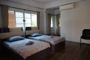 two beds in a room with two windows at baan wongsupar in Suan Phung