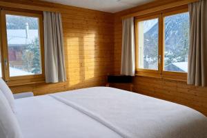 a bedroom with a white bed and two windows at Chalet Montis in Bellwald