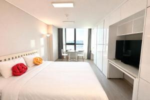 a bedroom with a bed with orange pillows and a television at 더 디셈버스테이 인 한라 in Taeam