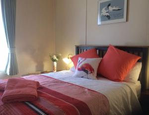 a bedroom with a bed with red and orange pillows at Kookaburra Cottage in Castlemaine