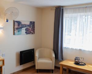 a living room with a chair and a television at Travel Plaza Hotel in Desborough