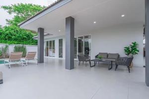 a patio with chairs and a couch and a table at 63 Jomtien Beach villa วิลล่าใกล้หาดจอมเทียน 這棟別墅距離海灘不遠 in Jomtien Beach