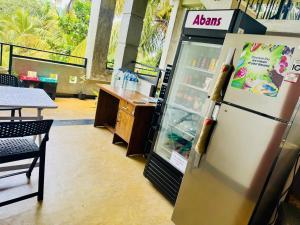 a refrigerator in a restaurant with a table and a counter at Camellia Unawatuna in Unawatuna