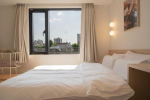 a white bed in a room with a large window at Anook Hotel Daejeon Daeheung in Daejeon