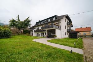 a large white house with a grassy yard in front of it at Hotel Pohorje in Maribor