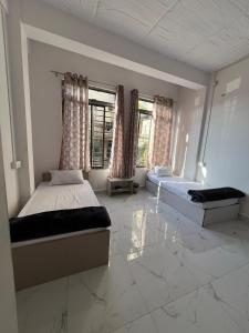 a bedroom with two beds and two windows at Aizawl View Hotel in Āīzawl