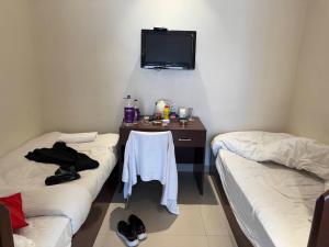 a room with two beds and a table with a tv on the wall at Hotel Fort in Patna