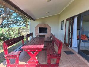 a red picnic table with two benches on a patio at Shore Breakers in Shelly Beach