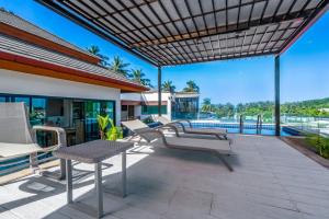 an outdoor patio with tables and chairs and a pool at Surin Sabai Residence near Surin Beach in Surin Beach