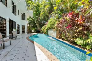 a swimming pool in a garden next to a house at Seascape Luxury Beachfront House in Clifton Beach