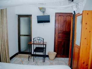 a bedroom with a table and a chair and a door at Arusha Centre Rooms in Arusha