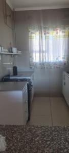 a small kitchen with white cabinets and a window at Locsona flat in Margate +7 photos