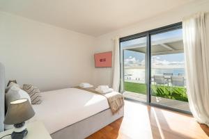 a bedroom with a bed and a view of the ocean at GuestReady - The Ocean El Cid in Fajã da Ovelha