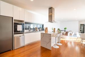 a kitchen with white cabinets and a kitchen island with stools at GuestReady - The Ocean El Cid in Fajã da Ovelha +55 photos