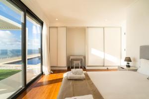 a bedroom with a bed and a large window at GuestReady - The Ocean El Cid in Fajã da Ovelha