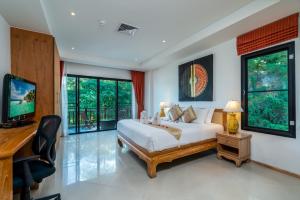 a bedroom with a bed and a desk and a television at Surin Sabai Residence near Surin Beach in Surin Beach
