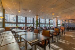 a restaurant with tables and chairs and windows at Leonardo Hotel Utrecht City Center in Utrecht +93 photos