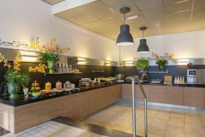 a restaurant with a counter with plants on it at Leonardo Hotel Utrecht City Center in Utrecht