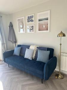 a blue couch in a living room with pictures on the wall at 1 Bed House On The Beach in St Peter