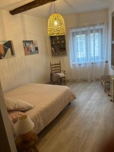 a bedroom with a bed and a chair and a chandelier at La Pause Bonheur La Campagnarde in Luc-sur-Orbieu