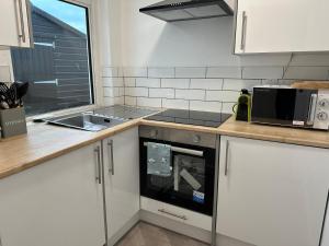 a kitchen with a stove and a sink and a microwave at 1 Bed House On The Beach in St Peter